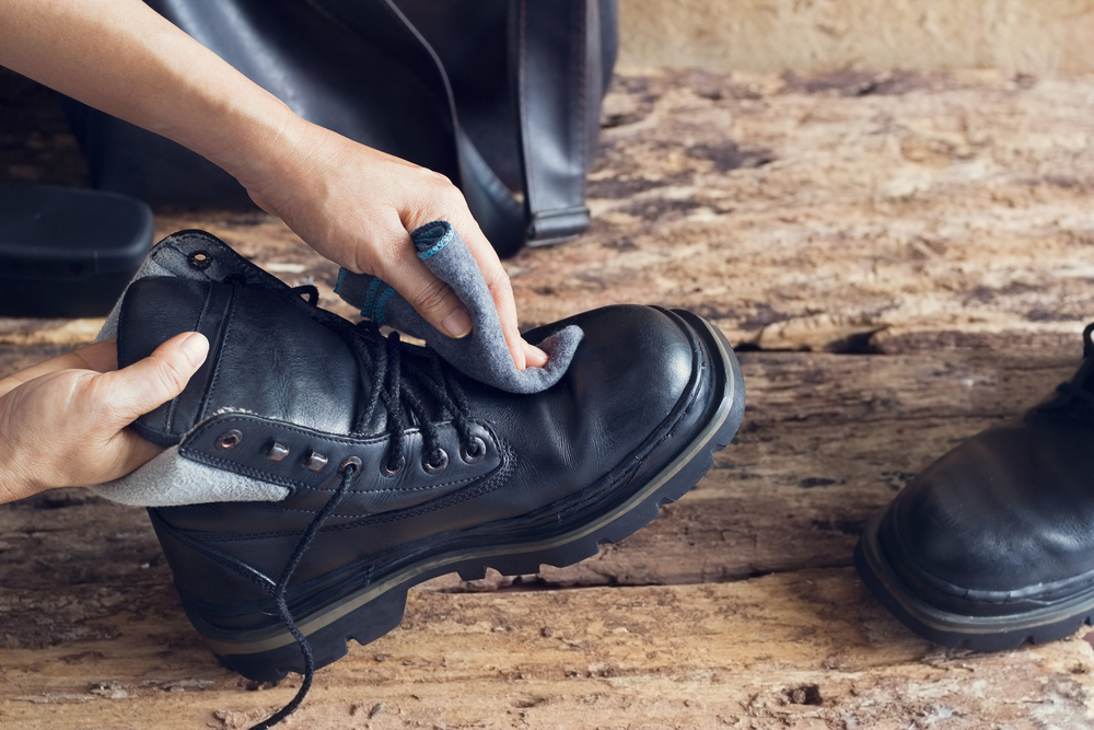 A black chucky boot being polished with a soft cloth.