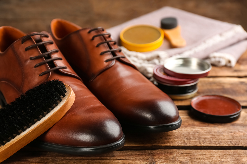 A leather shoe being cleaned with a cloth.